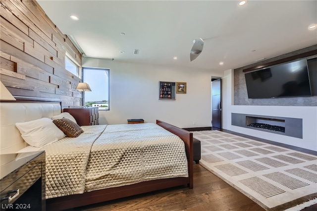 bedroom with dark wood-type flooring and a fireplace