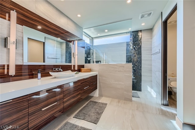 bathroom featuring tile flooring, vanity, toilet, and tile walls