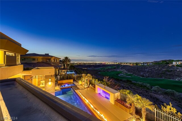 pool at dusk featuring a jacuzzi