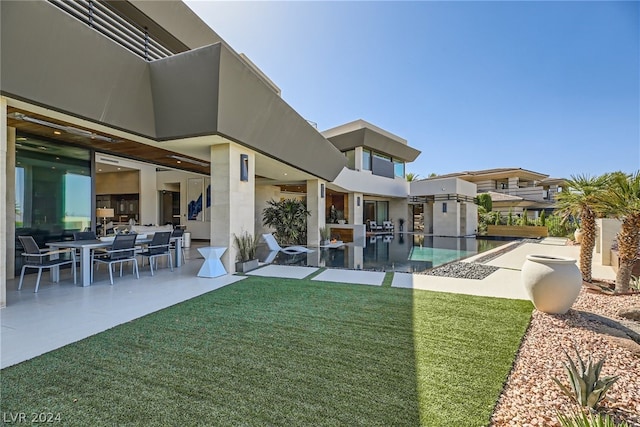 back of house featuring a yard, stucco siding, and a patio