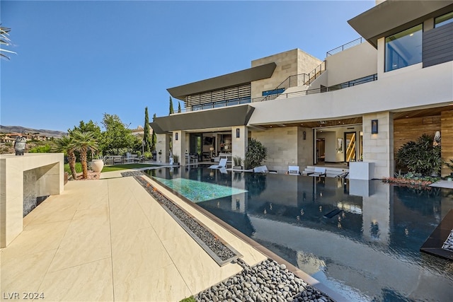 view of swimming pool featuring an infinity pool and a patio