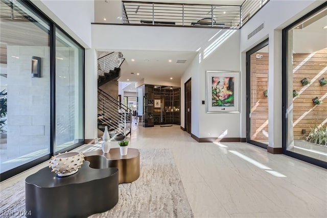 interior space featuring visible vents, stairway, a towering ceiling, and baseboards