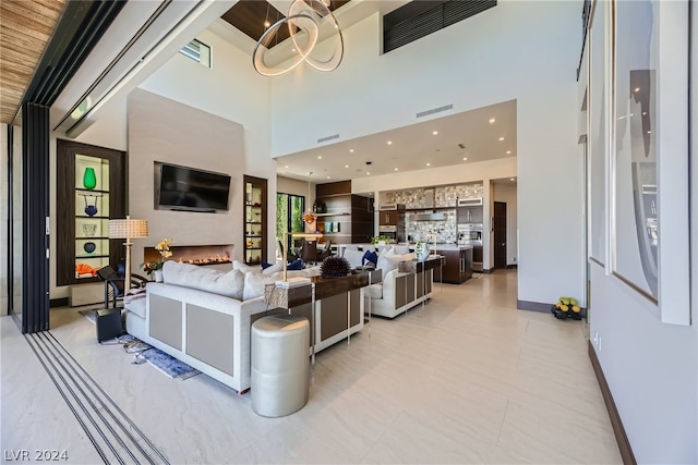 living room with a notable chandelier, a towering ceiling, and light tile flooring