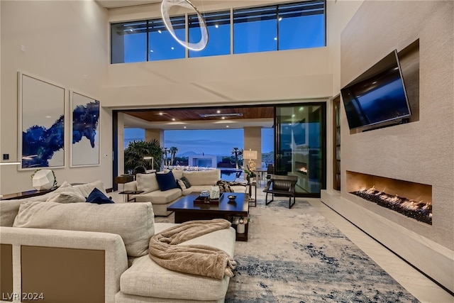 living area featuring a lit fireplace, a high ceiling, and wood finished floors