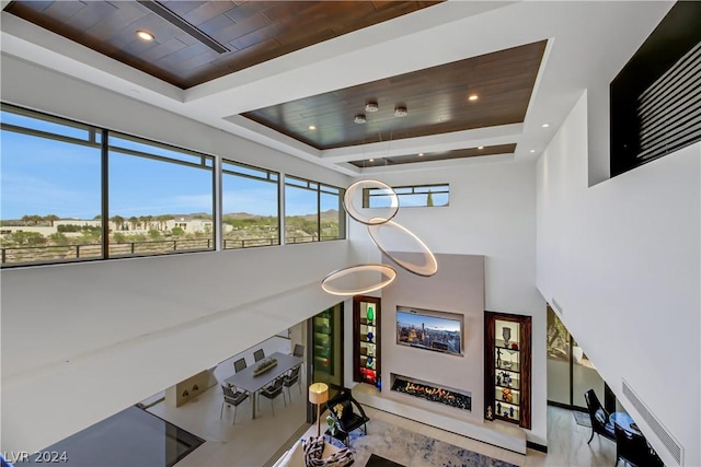 living area featuring a wealth of natural light, a tray ceiling, and wood ceiling