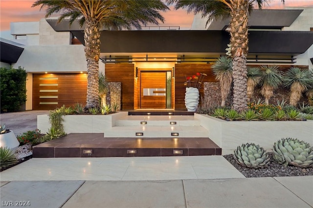 exterior entry at dusk featuring a garage