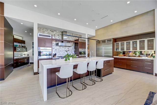 kitchen with a spacious island, modern cabinets, appliances with stainless steel finishes, light countertops, and a sink