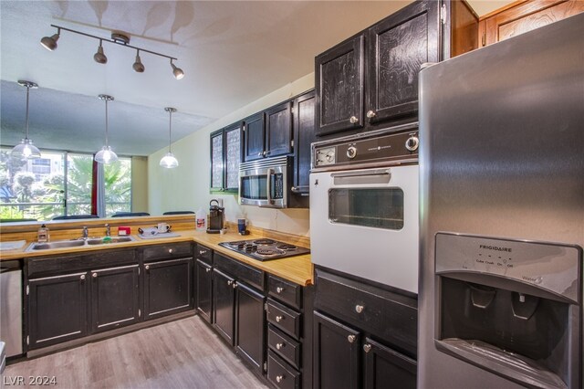 kitchen featuring light hardwood / wood-style floors, stainless steel appliances, pendant lighting, rail lighting, and sink