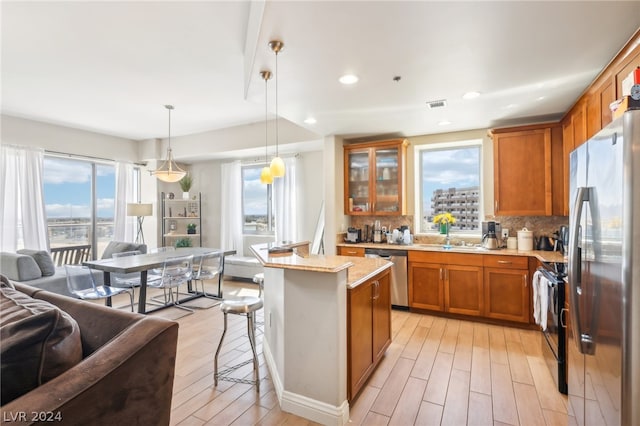 kitchen with a kitchen bar, decorative light fixtures, light hardwood / wood-style flooring, a kitchen island, and stainless steel appliances