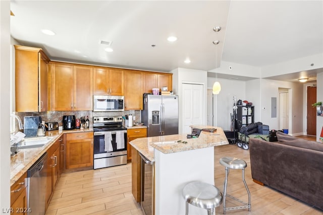 kitchen featuring a kitchen island, light stone counters, a breakfast bar area, and appliances with stainless steel finishes