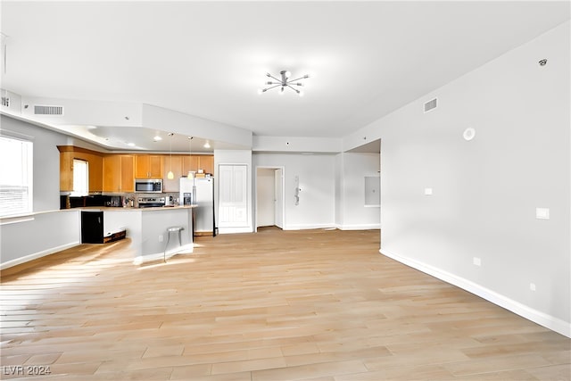 kitchen with stainless steel appliances, a kitchen breakfast bar, and light hardwood / wood-style flooring