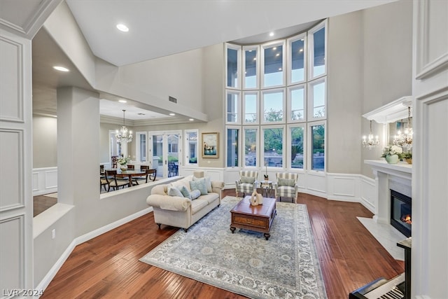 living room with crown molding, dark hardwood / wood-style flooring, a chandelier, a premium fireplace, and a towering ceiling