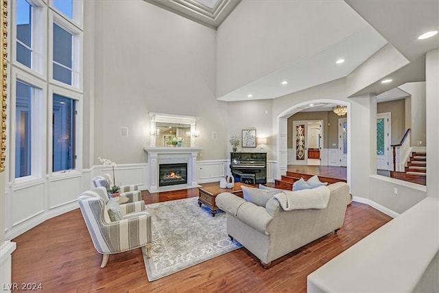 living room with a premium fireplace, wood-type flooring, and a high ceiling