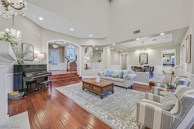 living room featuring a tray ceiling, a notable chandelier, a high ceiling, and hardwood / wood-style floors