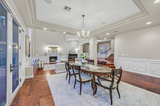 dining space with a notable chandelier, hardwood / wood-style flooring, and a tray ceiling