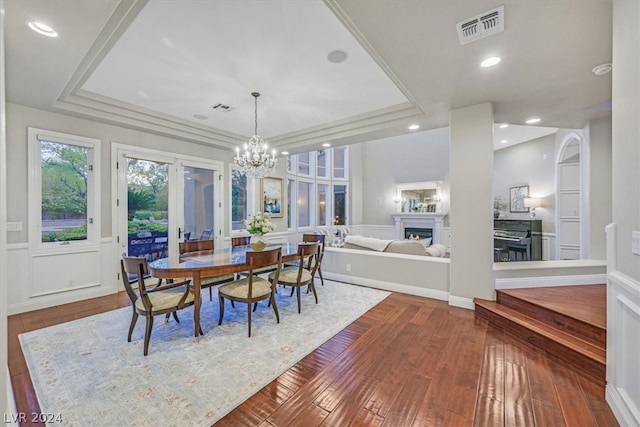 dining space with a notable chandelier, hardwood / wood-style floors, french doors, and a raised ceiling