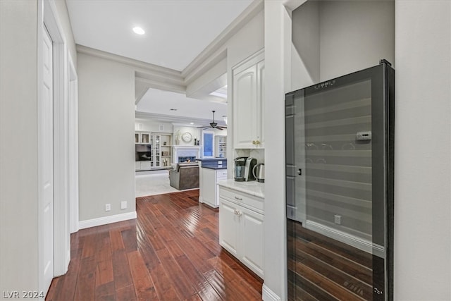 kitchen featuring white cabinetry, hardwood / wood-style flooring, wine cooler, ceiling fan, and a raised ceiling