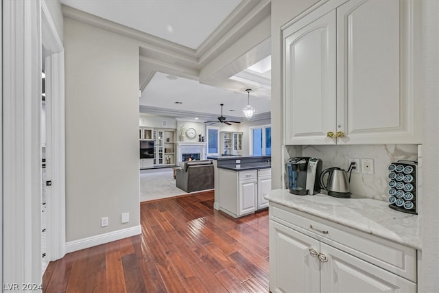 kitchen featuring dark hardwood / wood-style flooring, white cabinets, stone countertops, backsplash, and ceiling fan