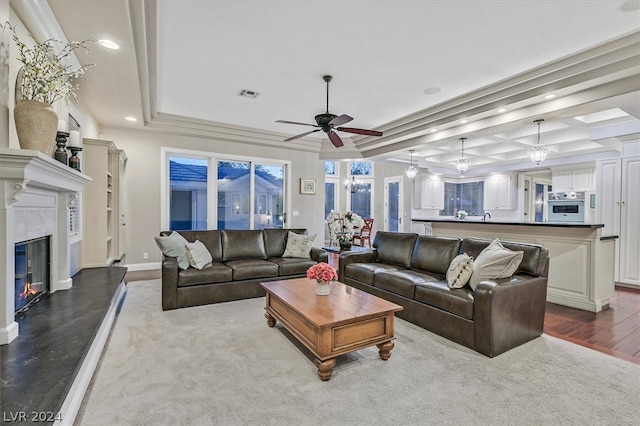 carpeted living room with a fireplace, ceiling fan, and a raised ceiling