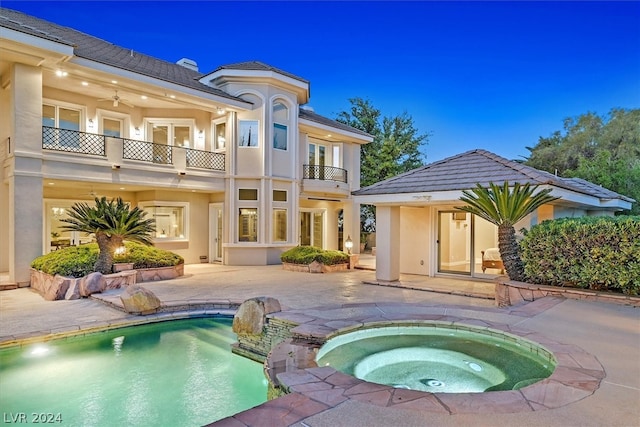 pool at night with a patio area and an in ground hot tub