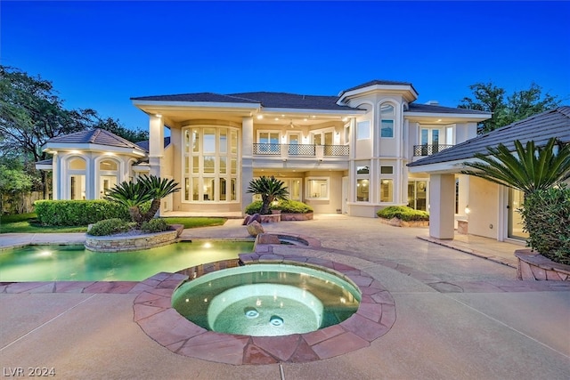 pool at twilight featuring a patio, an in ground hot tub, and french doors