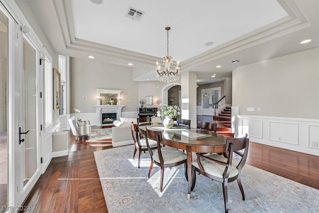 dining area with a notable chandelier, a tray ceiling, and dark hardwood / wood-style floors