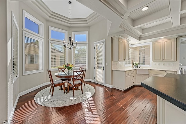 kitchen with coffered ceiling, a chandelier, tasteful backsplash, crown molding, and dark wood-type flooring