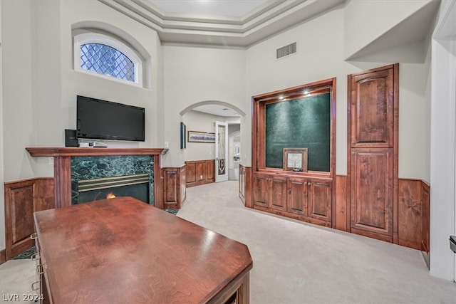 interior space featuring light carpet, a premium fireplace, crown molding, and a high ceiling