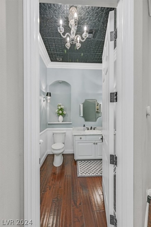 bathroom with a chandelier, vanity with extensive cabinet space, hardwood / wood-style flooring, toilet, and crown molding