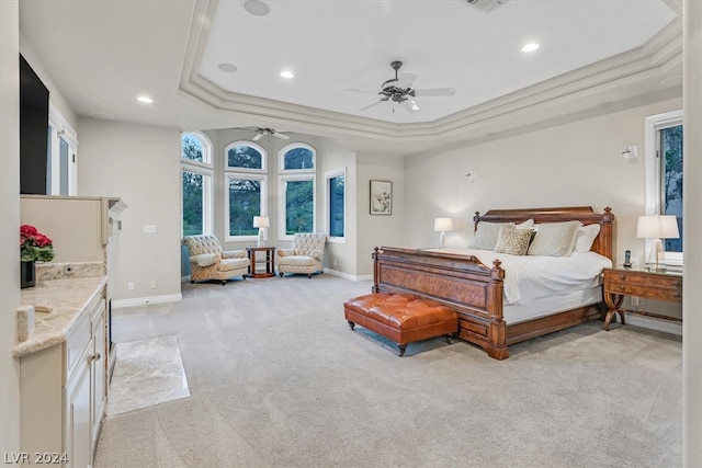 bedroom with ornamental molding, ceiling fan, light colored carpet, and a raised ceiling