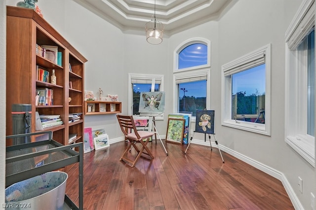 living area featuring ornamental molding, a tray ceiling, dark hardwood / wood-style floors, a high ceiling, and a notable chandelier