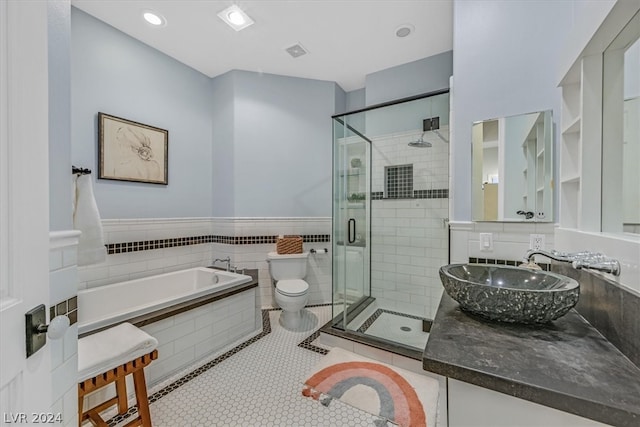 full bathroom with tile flooring, oversized vanity, separate shower and tub, tile walls, and toilet