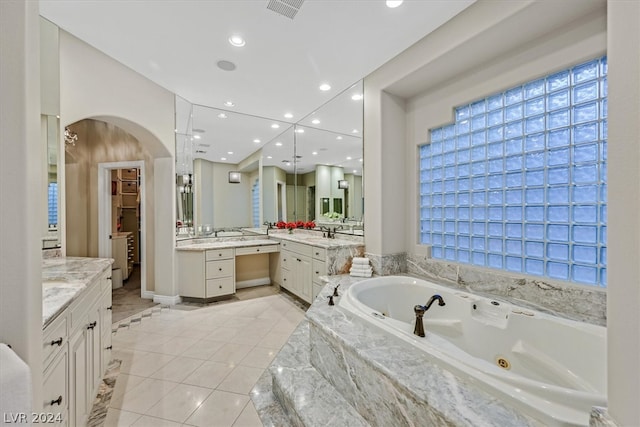 bathroom with tile flooring, tiled tub, and vanity