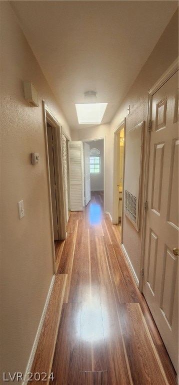 hallway featuring light wood-type flooring and a skylight