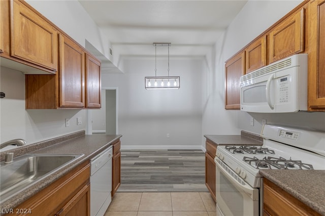 kitchen with hanging light fixtures, sink, white appliances, and light tile flooring