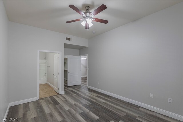 unfurnished bedroom featuring ceiling fan, a closet, a walk in closet, wood-type flooring, and connected bathroom