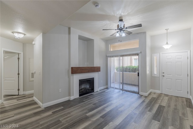 unfurnished living room featuring dark wood-type flooring and ceiling fan