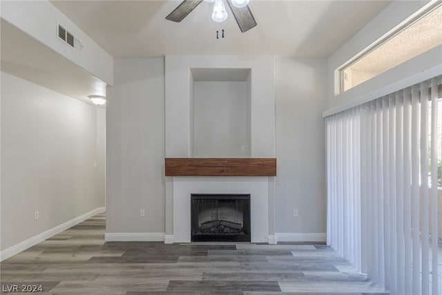 unfurnished living room featuring wood-type flooring, ceiling fan, and a tile fireplace