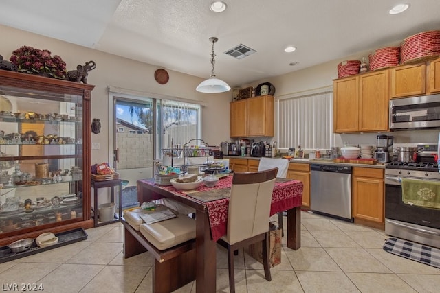 kitchen featuring stainless steel appliances, a textured ceiling, pendant lighting, and light tile floors