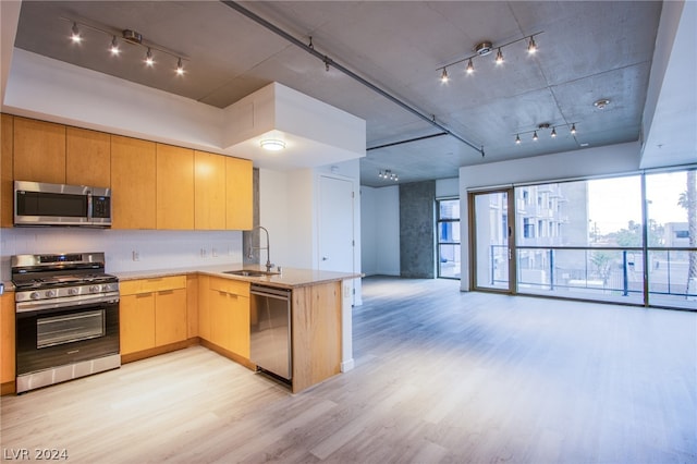 kitchen with appliances with stainless steel finishes, sink, rail lighting, and kitchen peninsula