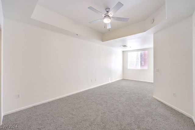 carpeted empty room featuring a tray ceiling and ceiling fan