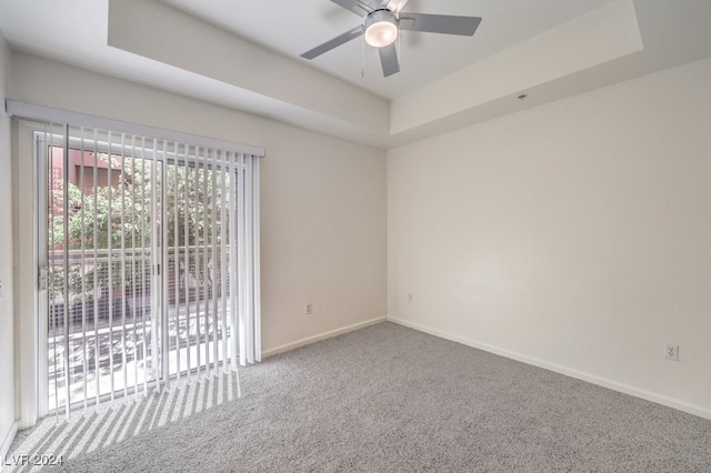 unfurnished room featuring a tray ceiling, carpet floors, and ceiling fan