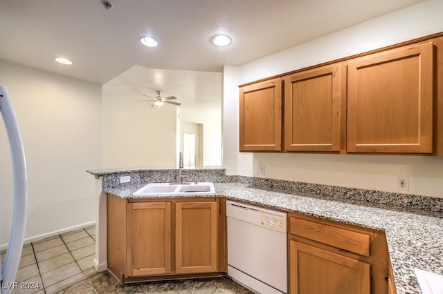 kitchen featuring white dishwasher, light stone counters, ceiling fan, sink, and kitchen peninsula