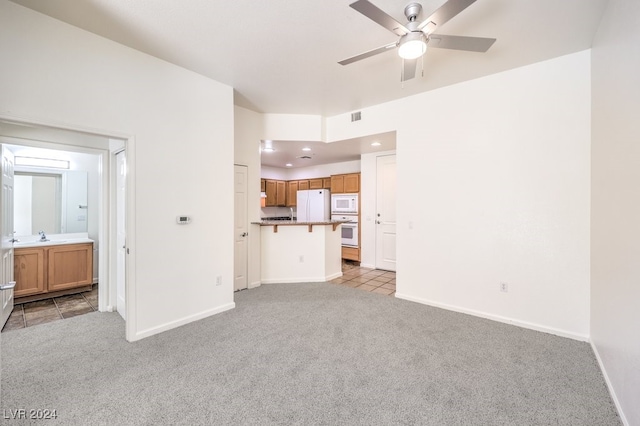 unfurnished living room with ceiling fan, sink, and light carpet