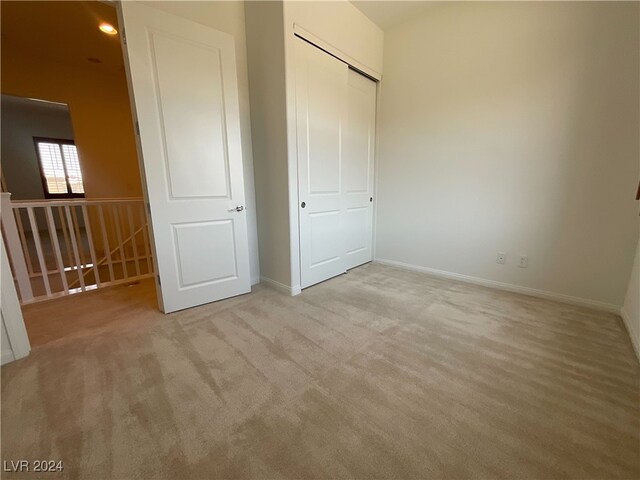 unfurnished bedroom with light carpet and a closet