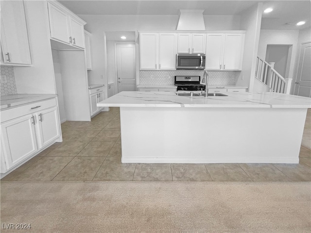 kitchen featuring appliances with stainless steel finishes, an island with sink, and white cabinets