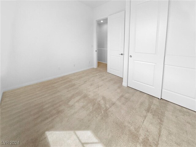 unfurnished bedroom with a closet and light colored carpet