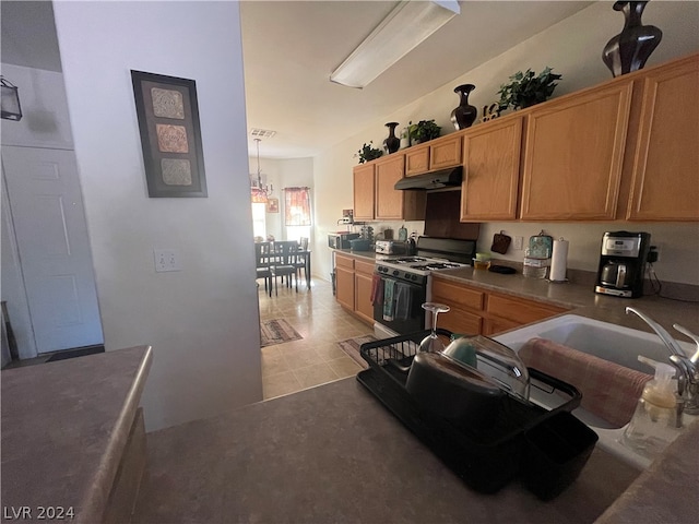 kitchen with white gas stove, sink, a notable chandelier, and light tile floors