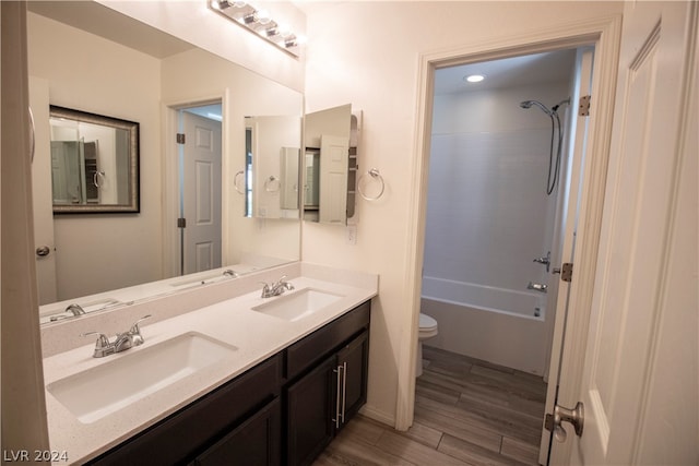 full bathroom featuring dual vanity, hardwood / wood-style flooring, toilet, and bathing tub / shower combination