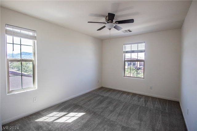 spare room featuring ceiling fan and dark colored carpet